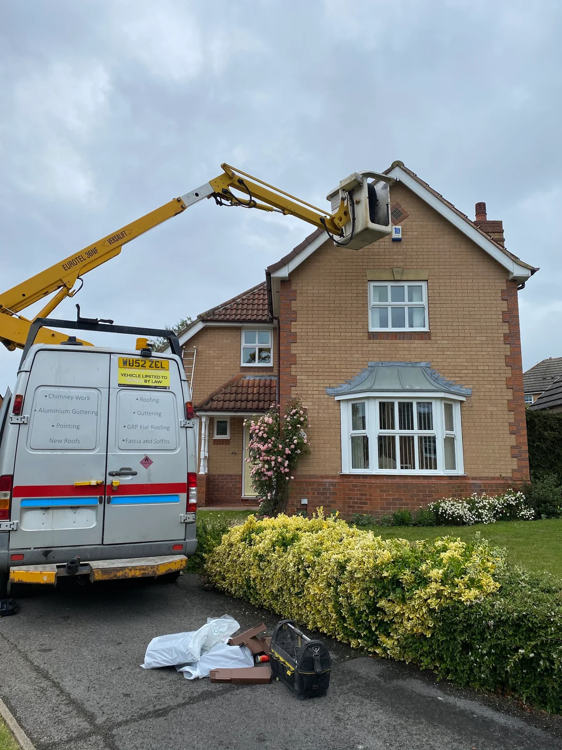 Roofing team working at roof level with an access vehicle