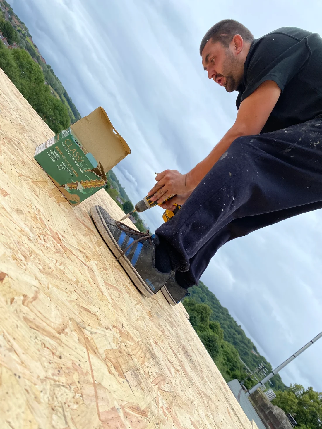 A roofer fastening decking during roofing work